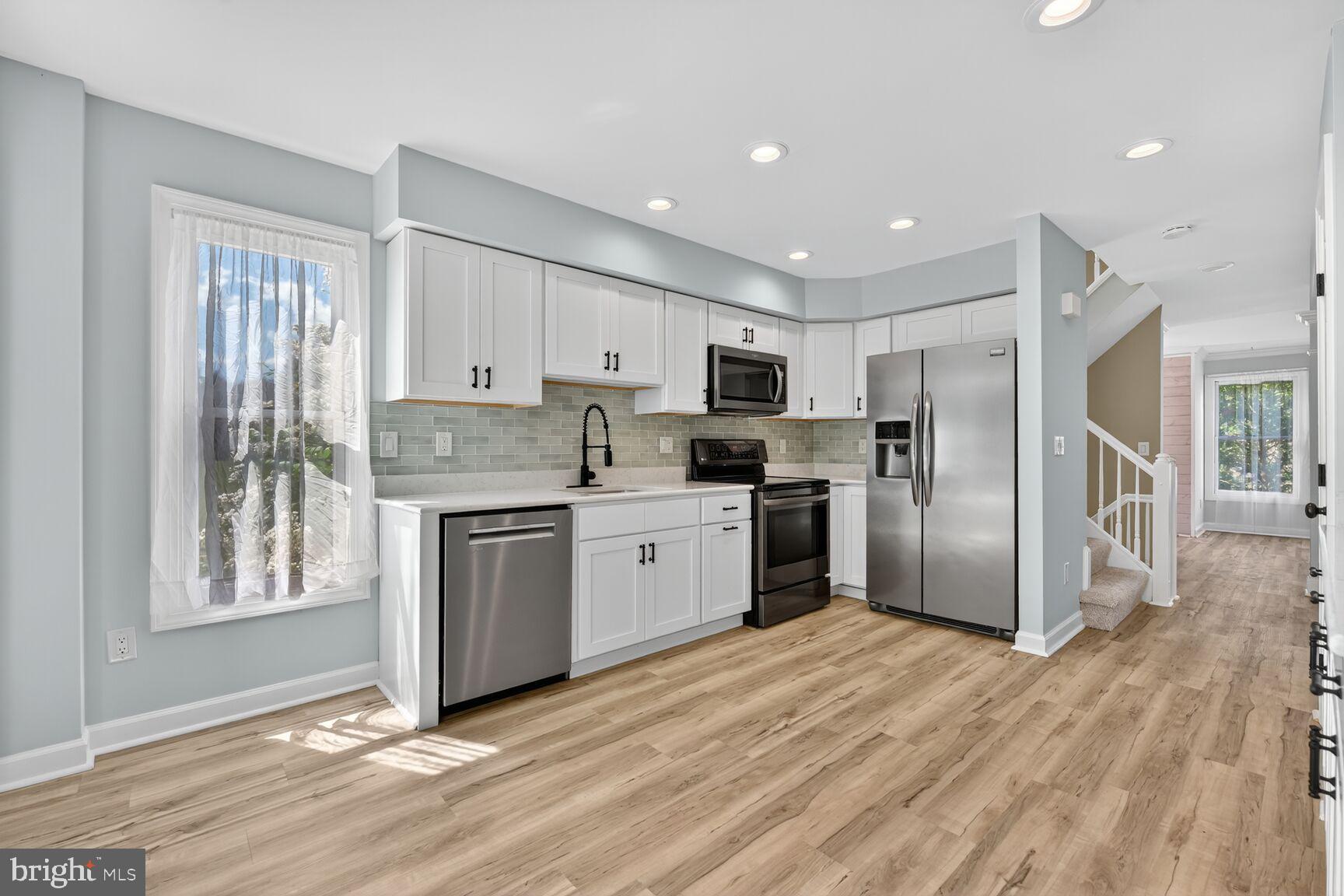 20970 Promontory Square Sterling, VA 20165 - Photo 3 of 44 a kitchen with granite countertop a refrigerator oven a sink dishwasher and white cabinets with wooden floor