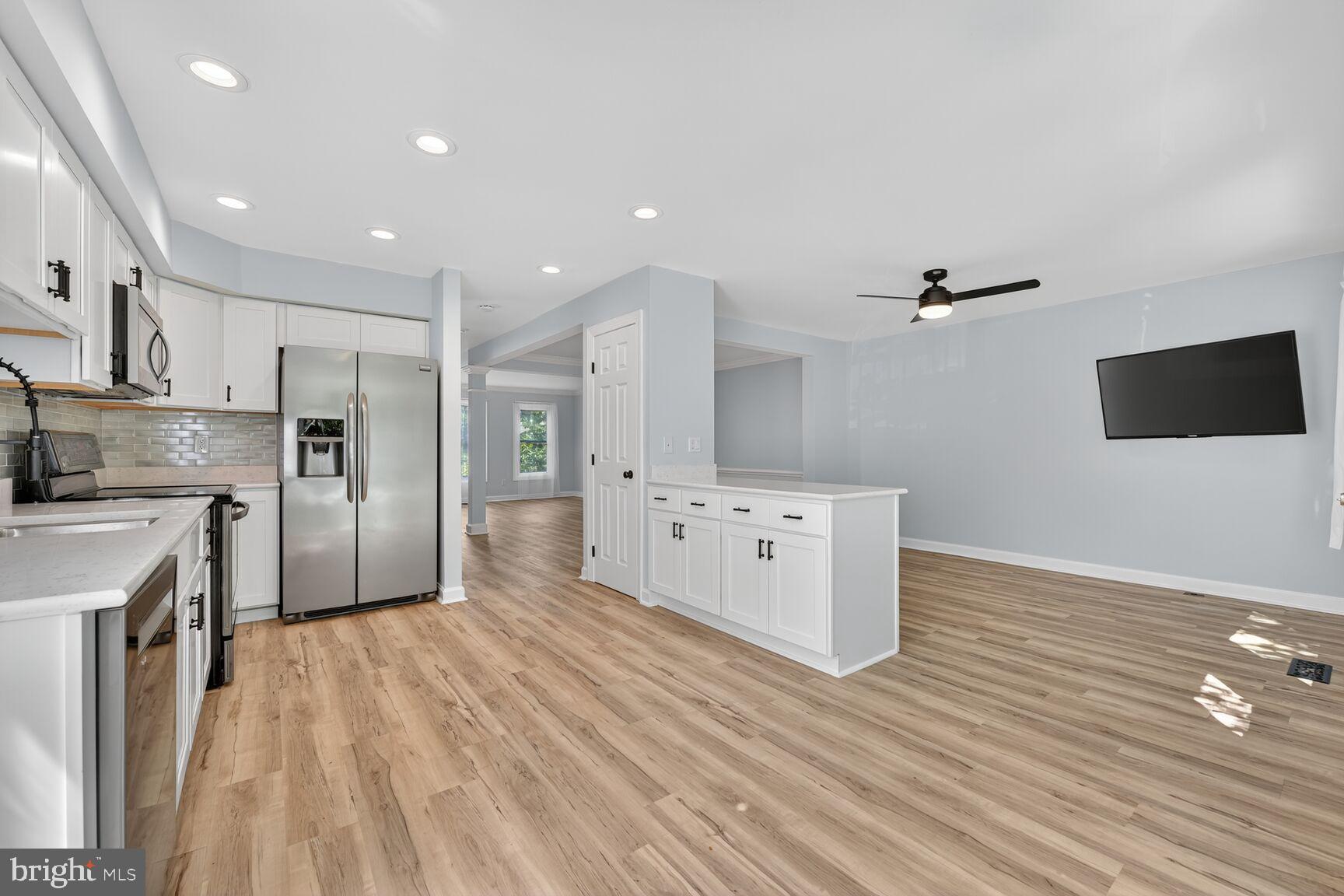 20970 Promontory Square Sterling, VA 20165 - Photo 5 of 44 a large kitchen with stainless steel appliances a large counter top a stove a refrigerator cabinets and a wooden floor
