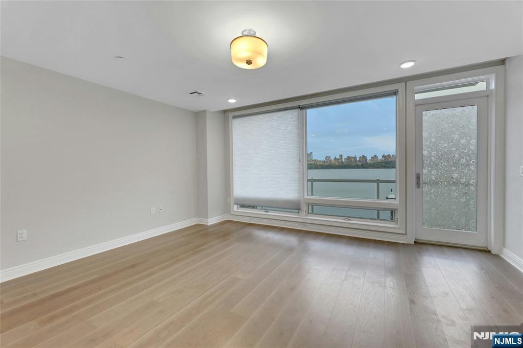 3 Somerset Lane, Unit 109 Edgewater, NJ 07020 - Photo 17 of 50 an empty room with wooden floor and windows