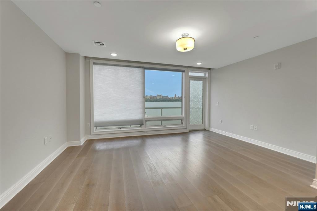 3 Somerset Lane, Unit 109 Edgewater, NJ 07020 - Photo 18 of 50 an empty room with wooden floor and windows