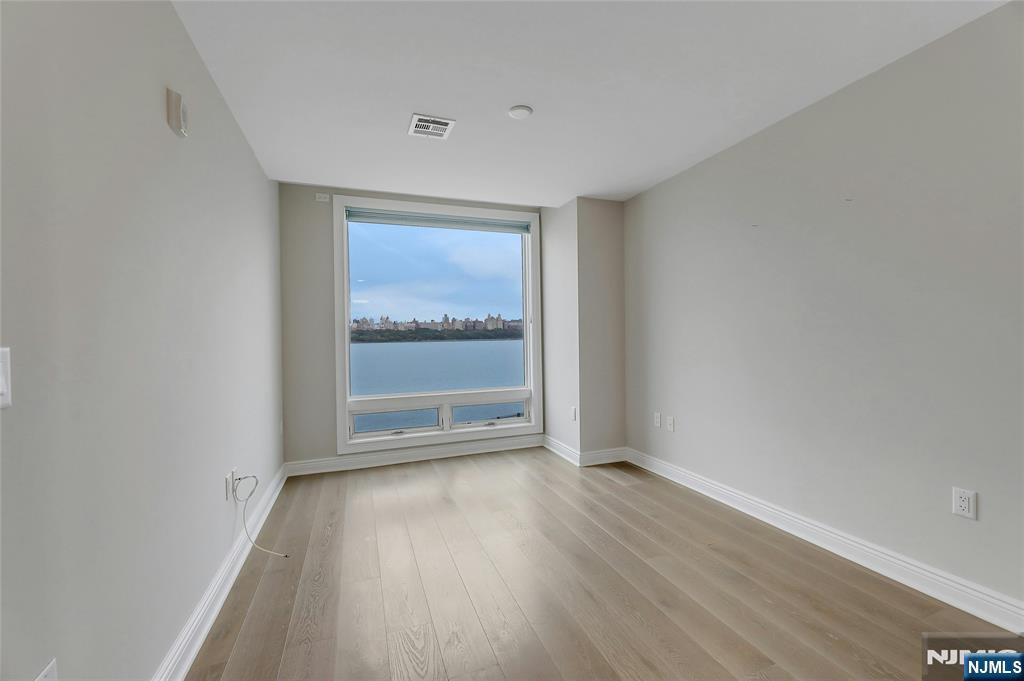3 Somerset Lane, Unit 109 Edgewater, NJ 07020 - Photo 26 of 50 a view of an empty room with wooden floor and a window