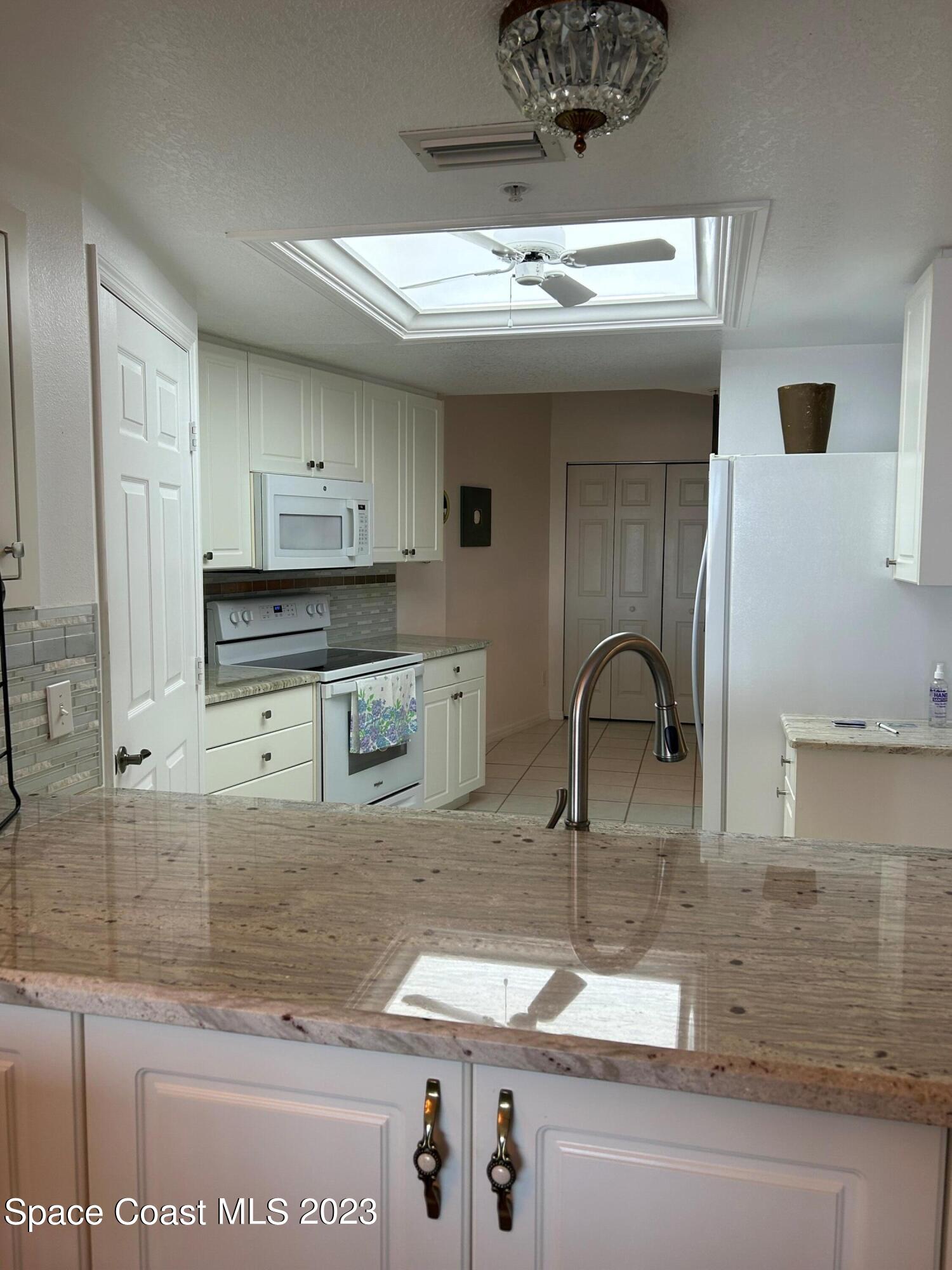 100 Riverside Drive, Unit 403 Cocoa, FL 32922 - Photo 7 of 30 a kitchen with kitchen island granite countertop a sink stainless steel appliances and cabinets