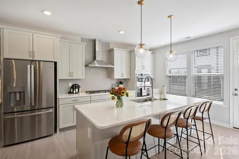 a kitchen with stainless steel appliances granite countertop a dining table chairs stove refrigerator and cabinets