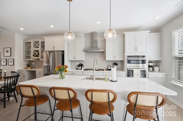 a kitchen with stainless steel appliances granite countertop a dining table chairs stove refrigerator and cabinets