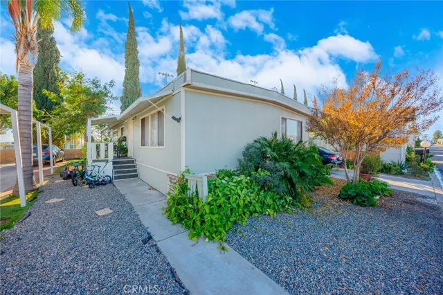 a backyard of a house with flower plants and large trees