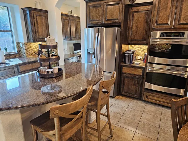 a kitchen with granite countertop a refrigerator stove and sink