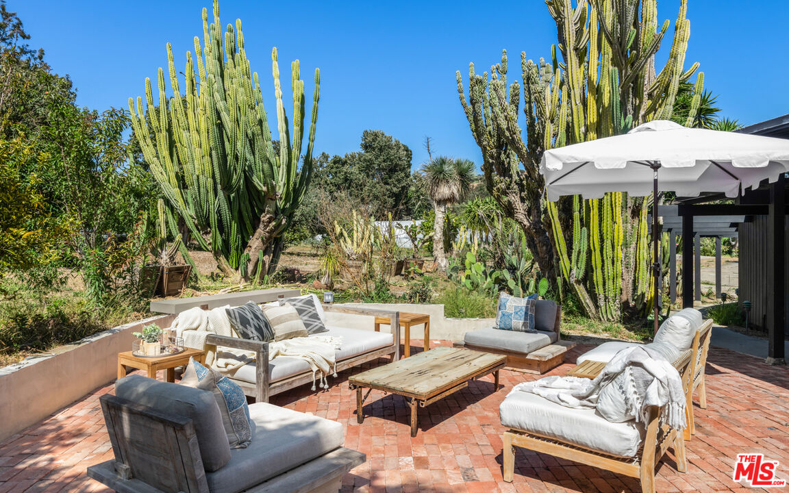 6009 Bonsall Drive Malibu, CA 90265 - Photo 11 of 49 a view of a patio with table and chairs potted plants and palm tree