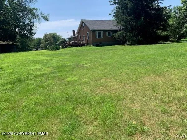 a view of a house next to a yard with big trees