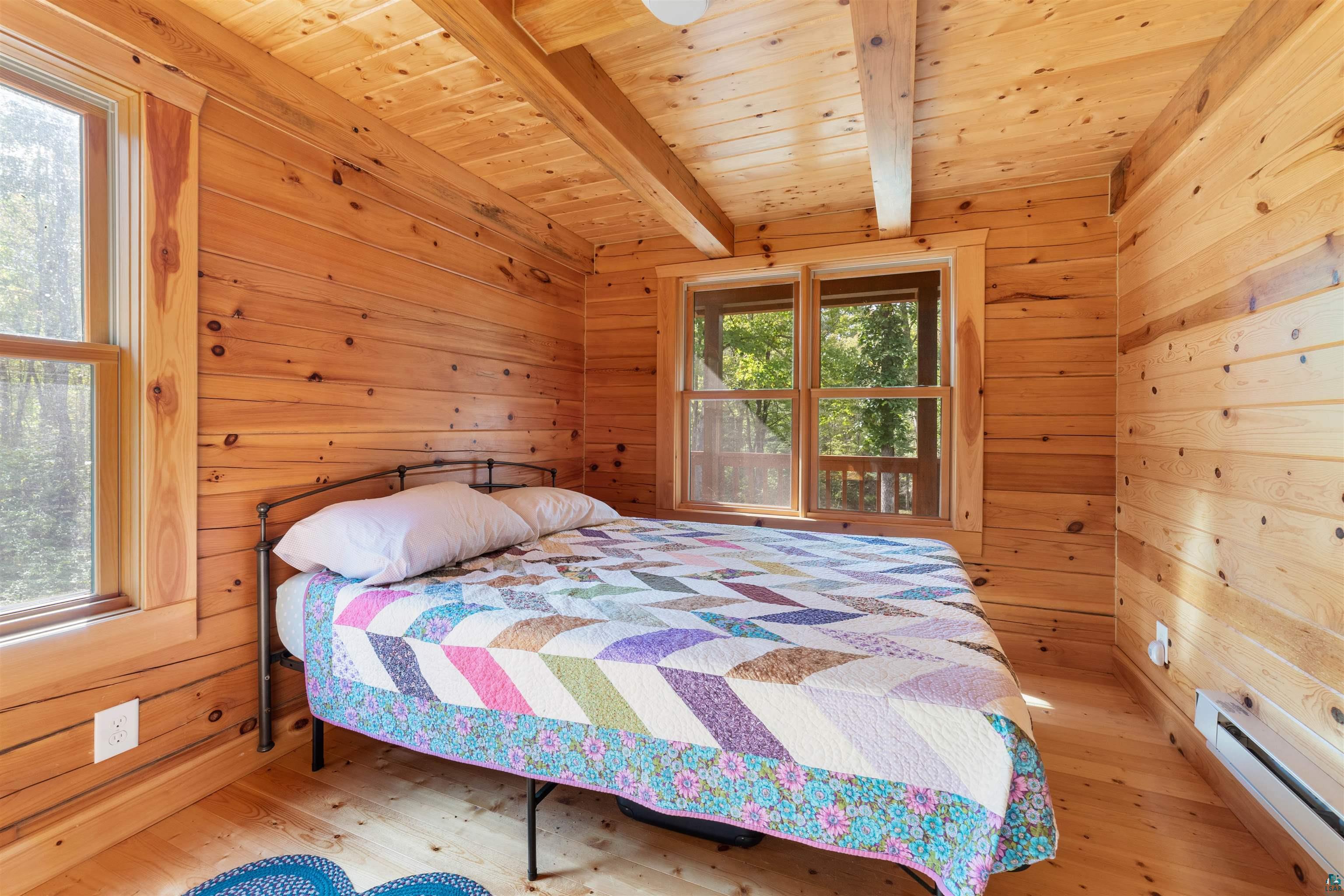 6711 South Jem Lane Lake Nebagamon, WI 54849 - Photo 11 of 28 Bedroom with light wood-type flooring, multiple windows, and beamed ceiling