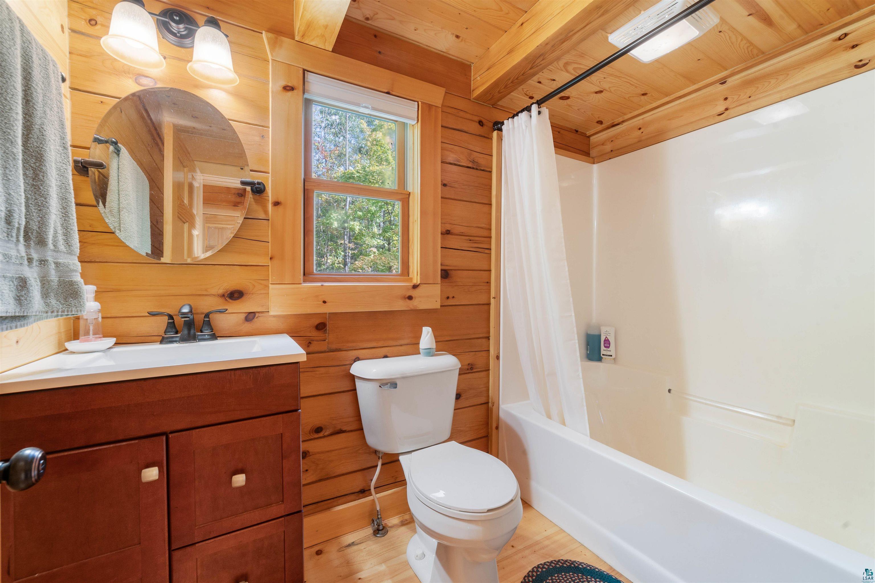 6711 South Jem Lane Lake Nebagamon, WI 54849 - Photo 13 of 28 Full bathroom featuring wood ceiling, wood walls, shower / bath combination with curtain, hardwood / wood-style flooring, and toilet