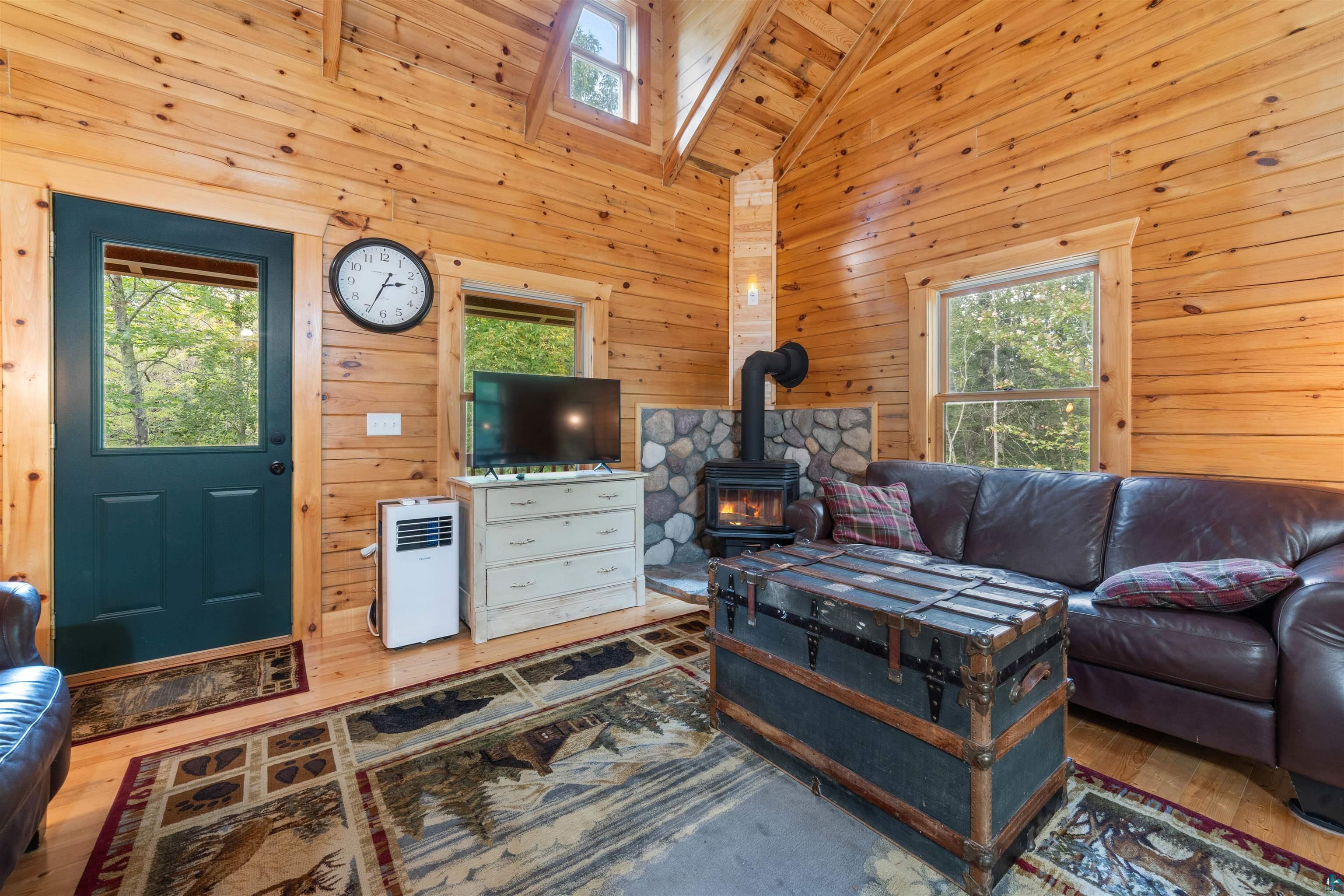 6711 South Jem Lane Lake Nebagamon, WI 54849 - Photo 8 of 28 Living room with wood ceiling, high vaulted ceiling, wood walls, a wood stove, and hardwood / wood-style flooring