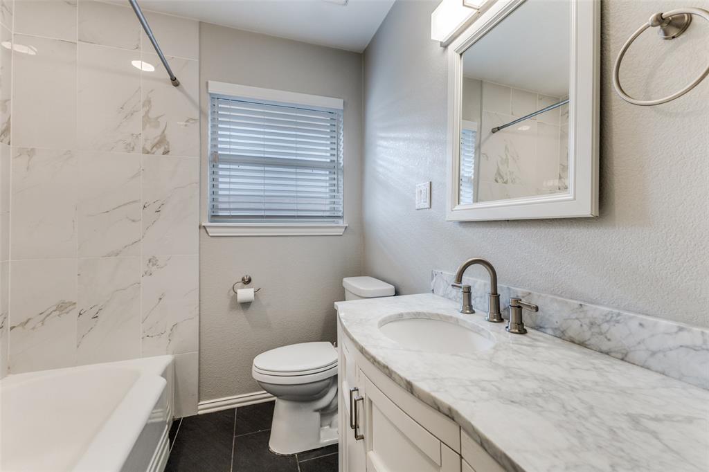 7128 Haverford Road Dallas, TX 75214 - Photo 12 of 24 a bathroom with a granite countertop toilet sink and mirror