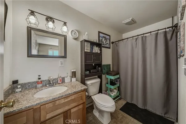 a bathroom with a granite countertop toilet a sink and a mirror