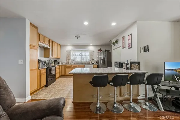 a living room with stainless steel appliances granite countertop a couch and a dining table with wooden floor