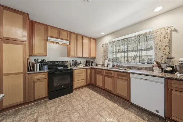 a kitchen with granite countertop a refrigerator stove top oven and sink