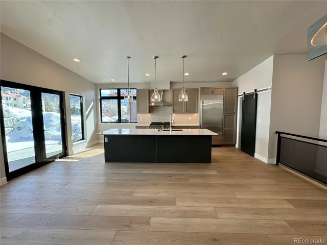 a large kitchen with kitchen island a large counter top stainless steel appliances and a large window