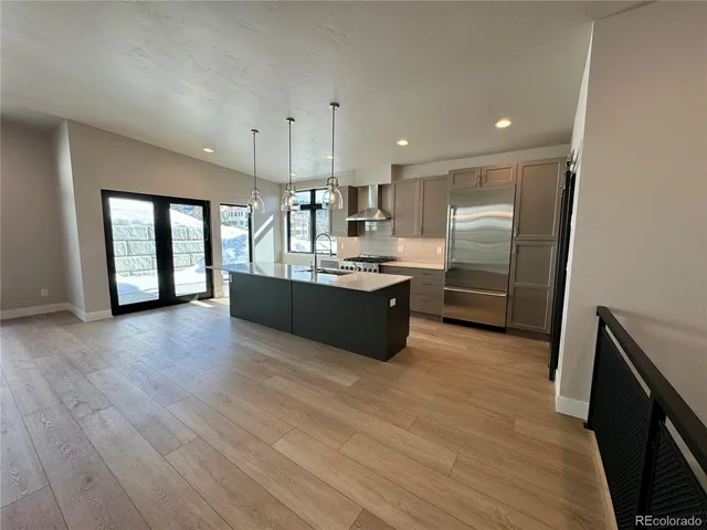 a large kitchen with stainless steel appliances granite countertop a large counter top a sink and a refrigerator