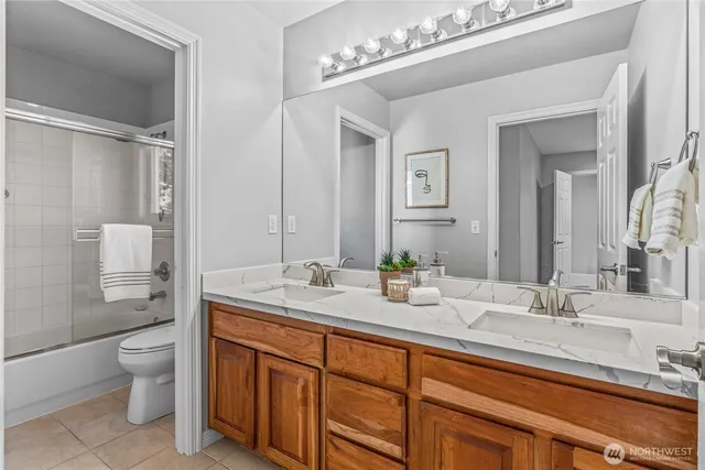 a spacious bathroom with a double vanity sink a mirror and a toilet