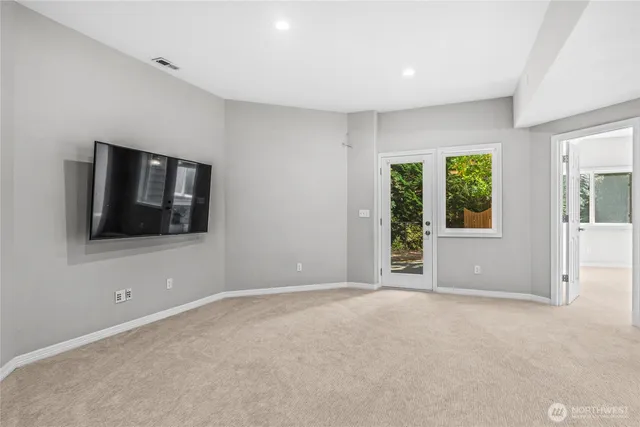 a view of an empty room with window and wooden floor