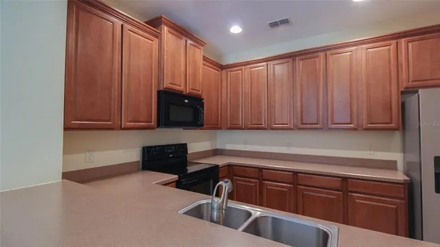 a kitchen with stainless steel appliances granite countertop wooden cabinets a refrigerator and a sink