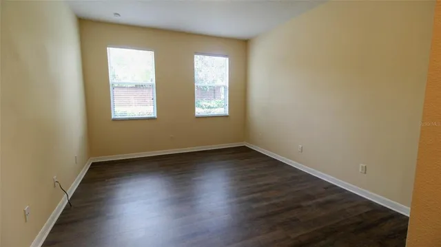 an empty room with wooden floor and windows