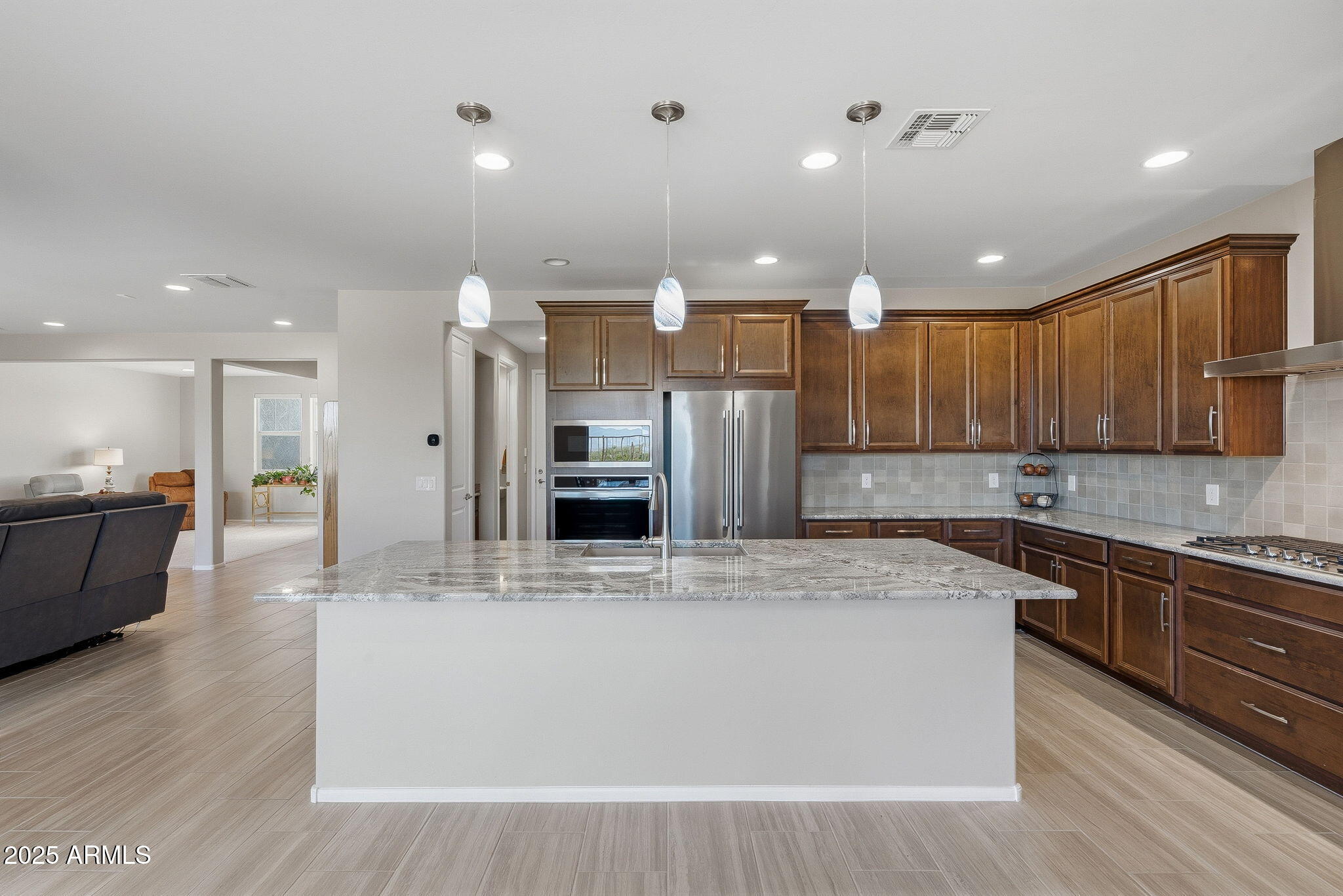 5439 South Sierra Prieta Trail Tucson, AZ 85747 - Photo 9 of 71 a large kitchen with stainless steel appliances kitchen island a large counter top and a stove top oven