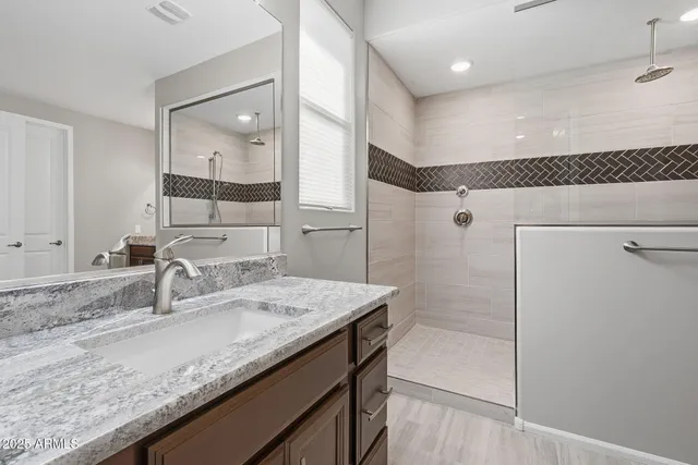 a bathroom with a granite countertop sink a mirror and a shower
