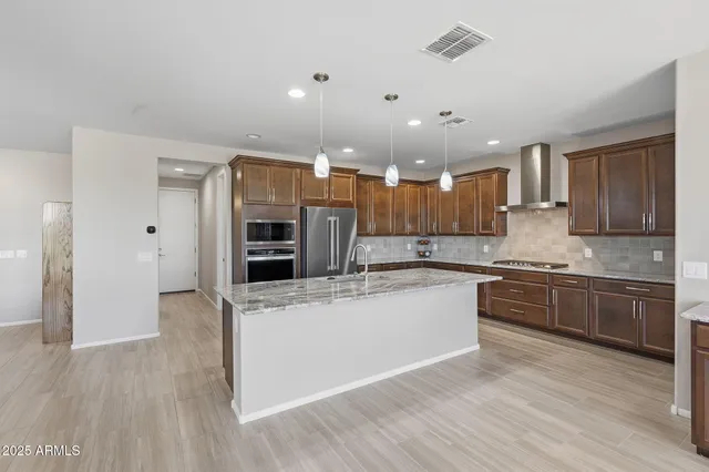 a large kitchen with stainless steel appliances kitchen island a large counter top and a stove top oven