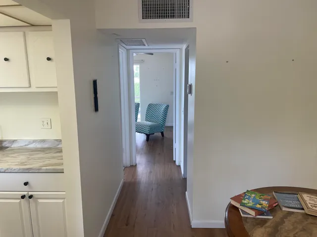 a view of a hallway with wooden floor and cabinet