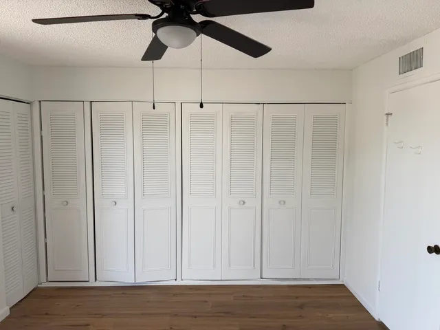 an empty room with wooden floor fan and windows