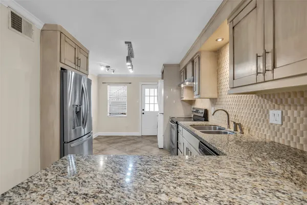 a kitchen with granite countertop a refrigerator and a sink