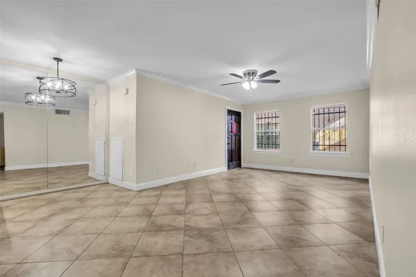 a view of an empty room with a chandelier fan and windows