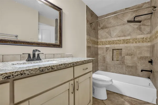 a bathroom with a granite countertop sink a toilet and shower