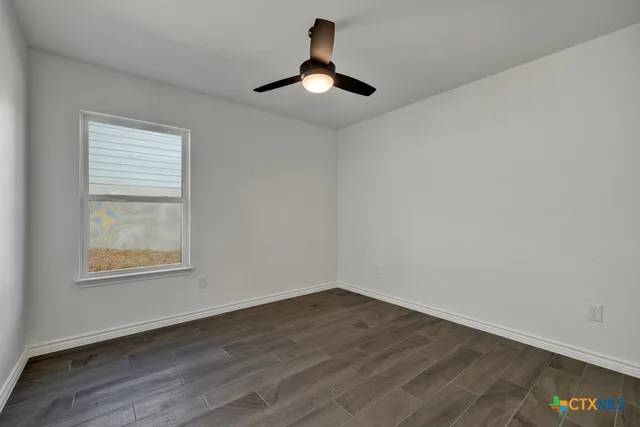 a big room with wooden floor a chandelier fan and windows