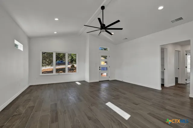 a view of empty room with wooden floor and fan