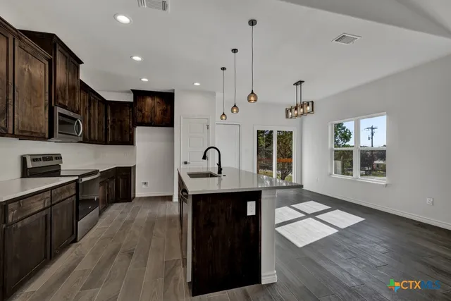 a kitchen with stainless steel appliances granite countertop a stove a sink dishwasher and a microwave oven with wooden floor