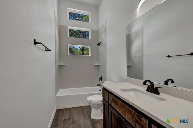 a bathroom with a granite countertop sink a toilet and a bathtub