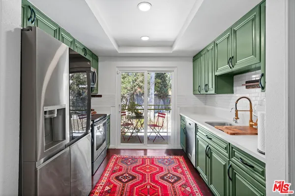 a kitchen with stainless steel appliances granite countertop a refrigerator a sink a stove top oven a washer and dryer