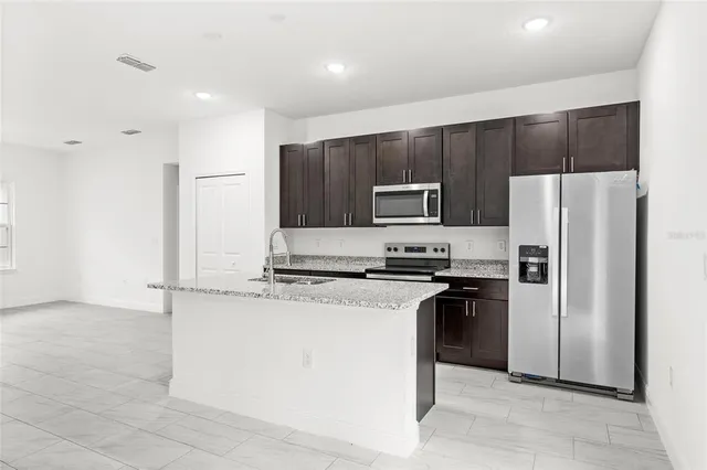 a kitchen with stainless steel appliances granite countertop a refrigerator a stove a sink and a microwave