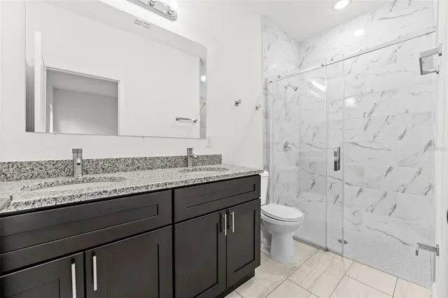 a bathroom with a granite countertop sink toilet and shower