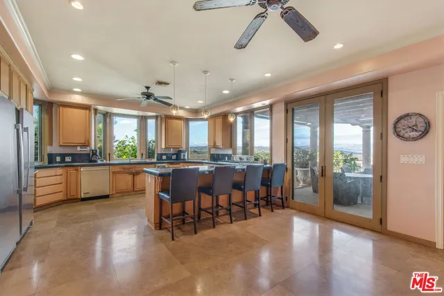 a kitchen with stainless steel appliances kitchen island granite countertop a refrigerator a sink a stove and white cabinets with wooden floor