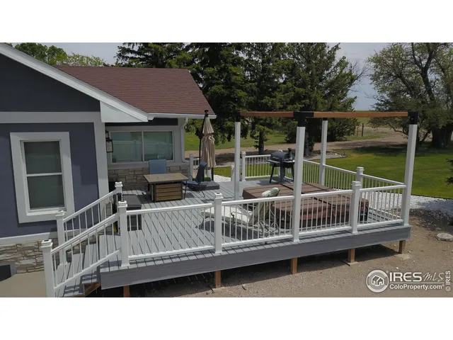 a view of a patio with couches table and chairs with wooden floor and fence