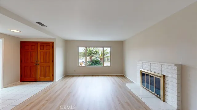 an empty room with windows fireplace and wooden floor