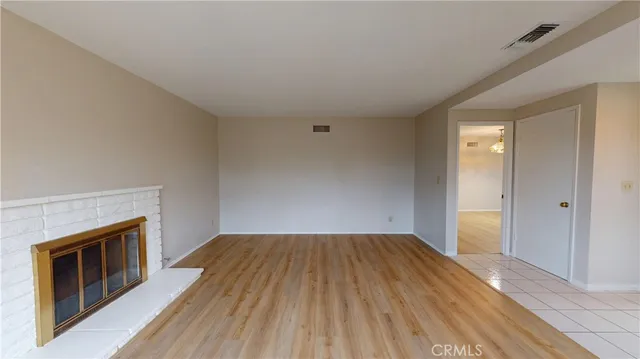 a view of empty room with wooden floor and fireplace