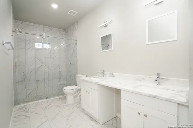 a bathroom with a granite countertop sink toilet and shower