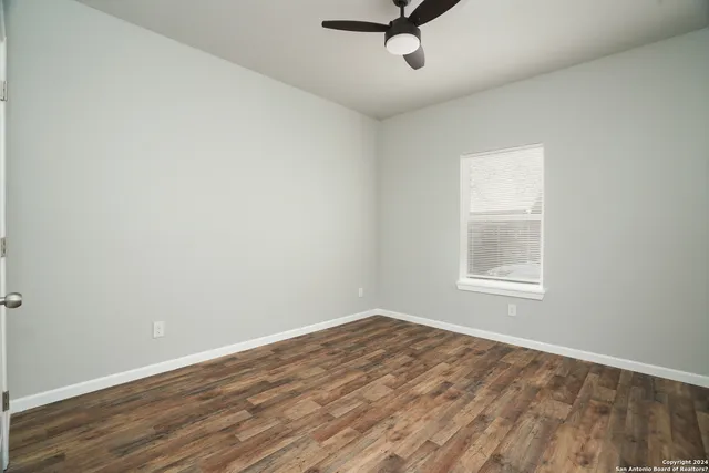 an empty room with a window and a ceiling fan