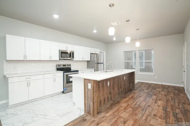 a large kitchen with kitchen island a sink stainless steel appliances and cabinets