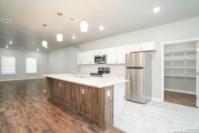 a kitchen with stainless steel appliances granite countertop a refrigerator a sink dishwasher a stove and a refrigerator with wooden floor