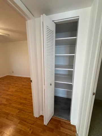 an empty room with wooden floor and a ceiling fan