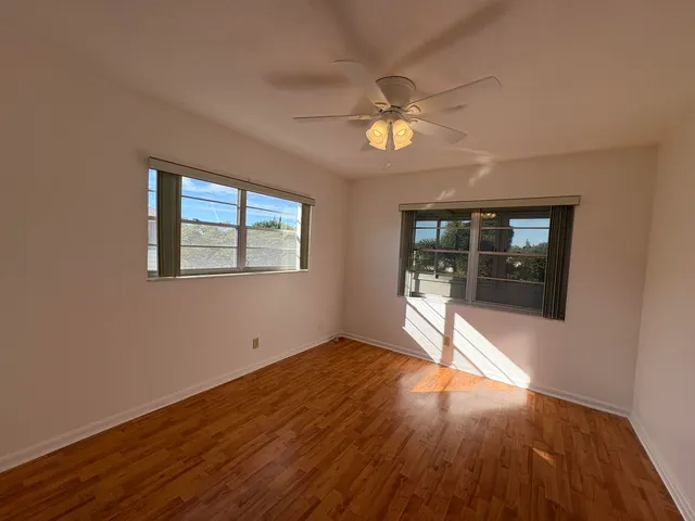 a view of empty room with wooden floor and fan